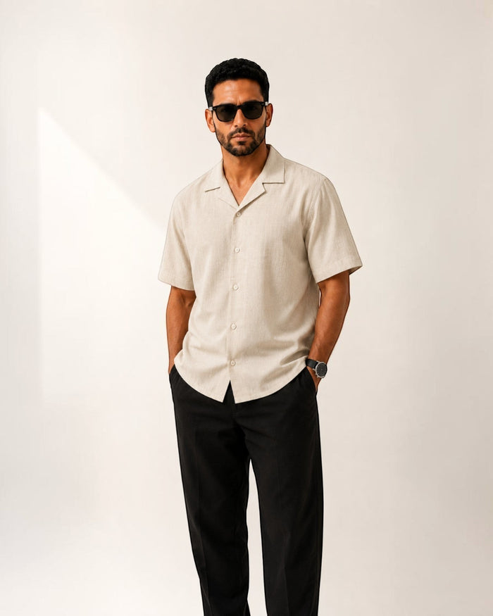 MU SHOP beige linen short-sleeve shirt with a soft collar and rounded hem, worn by a man with sunglasses.