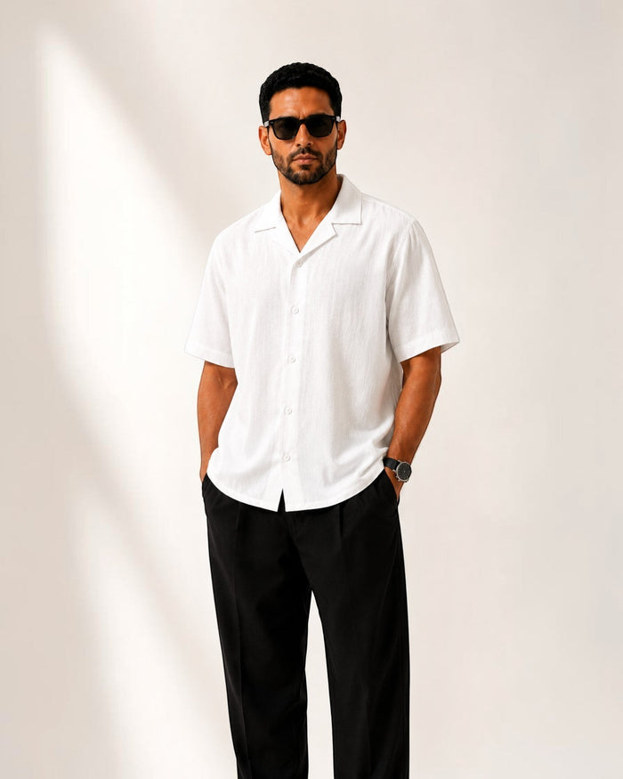 MU SHOP white linen short-sleeve shirt with a relaxed fit and spread collar, worn by a man with sunglasses.